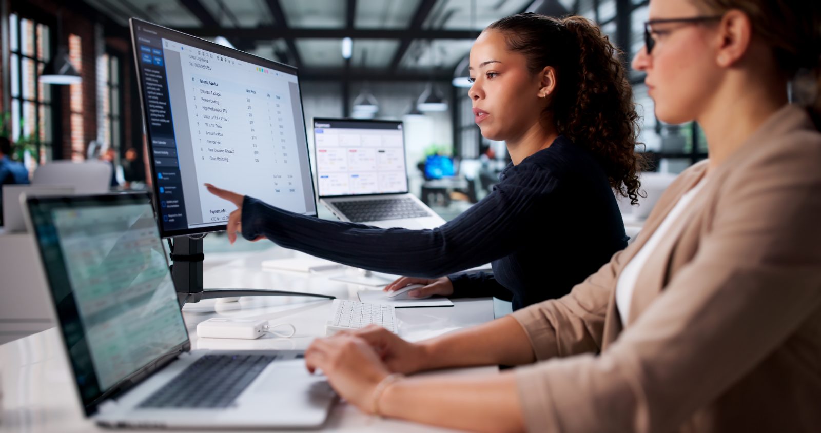 Two colleagues reviewing billing details on a computer screen